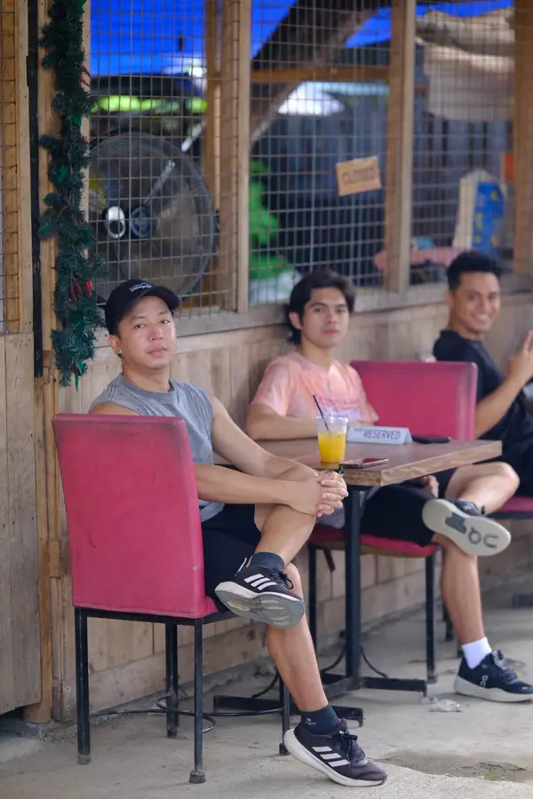 Three men sitting at a reserved outdoor table with a drink, taking a break from play at RC Rally Hub