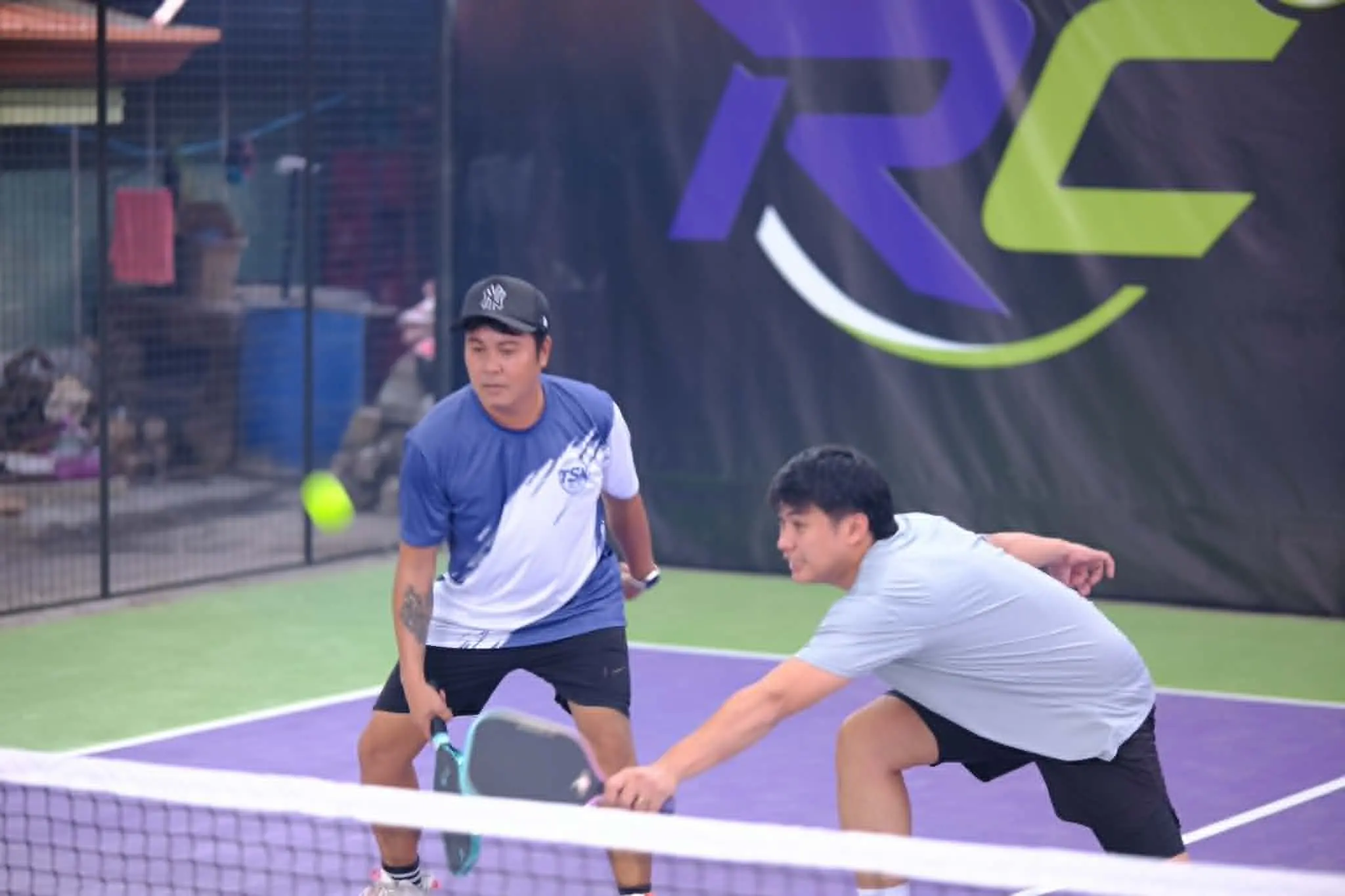 Mixed doubles tournament match at RC Rally Hub with an emcee hosting and a crowd of spectators